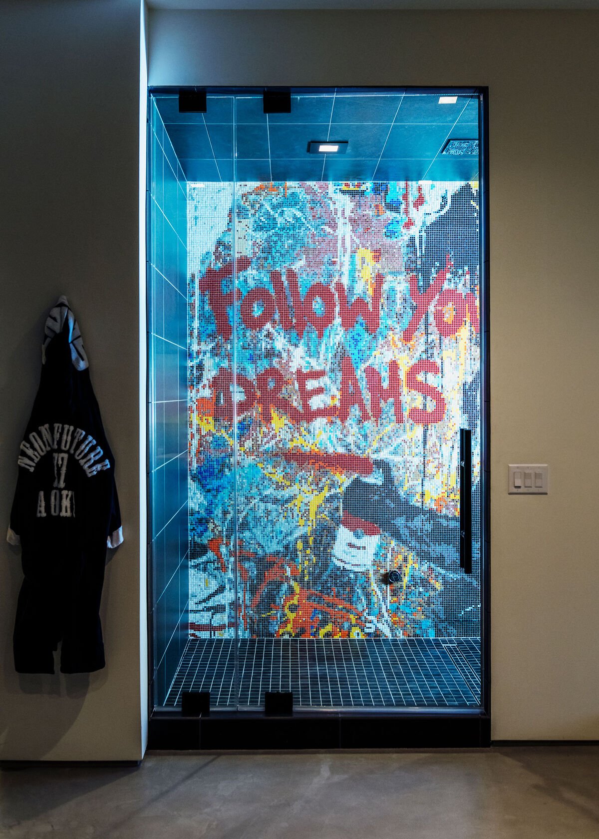 Một chiếc áo choàng tắm có tựa đề trong bộ ba album của Aoki's Neon Future treo bên cạnh một vòi hoa sen phủ đầy graffiti. Ảnh của Brian Guido cho Artsy.
